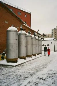 Sekrety kształtowania ceny oleju opałowego - wpływające czynniki i rozważania na ich temat Faceless couple walking near big industrial tanks on winter day